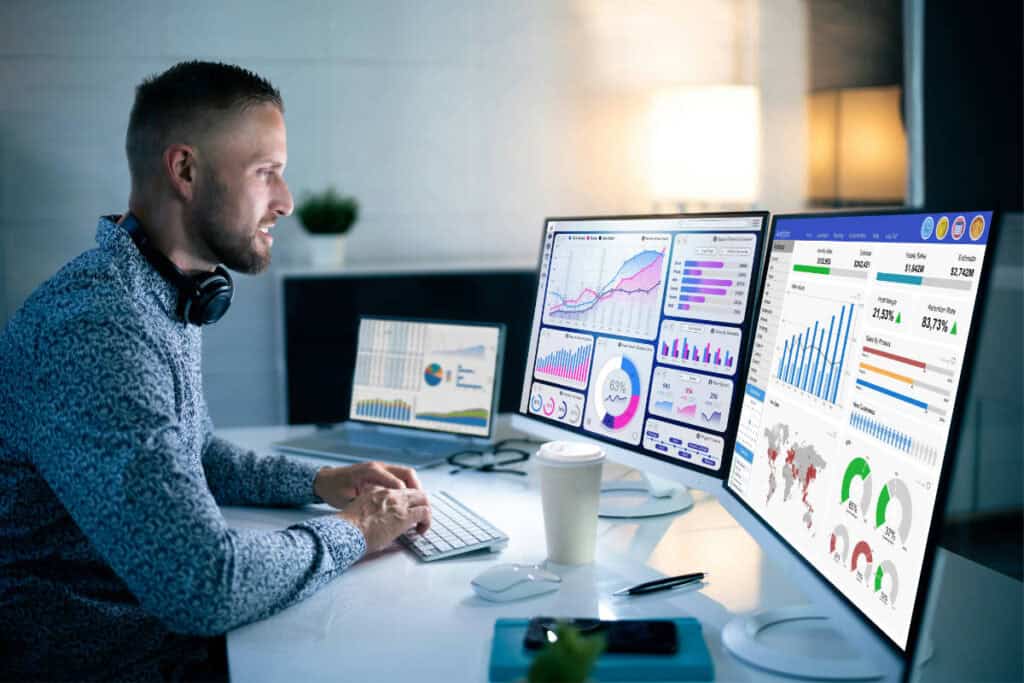 Web designer analyzing data on multiple screens for SEO and digital marketing.